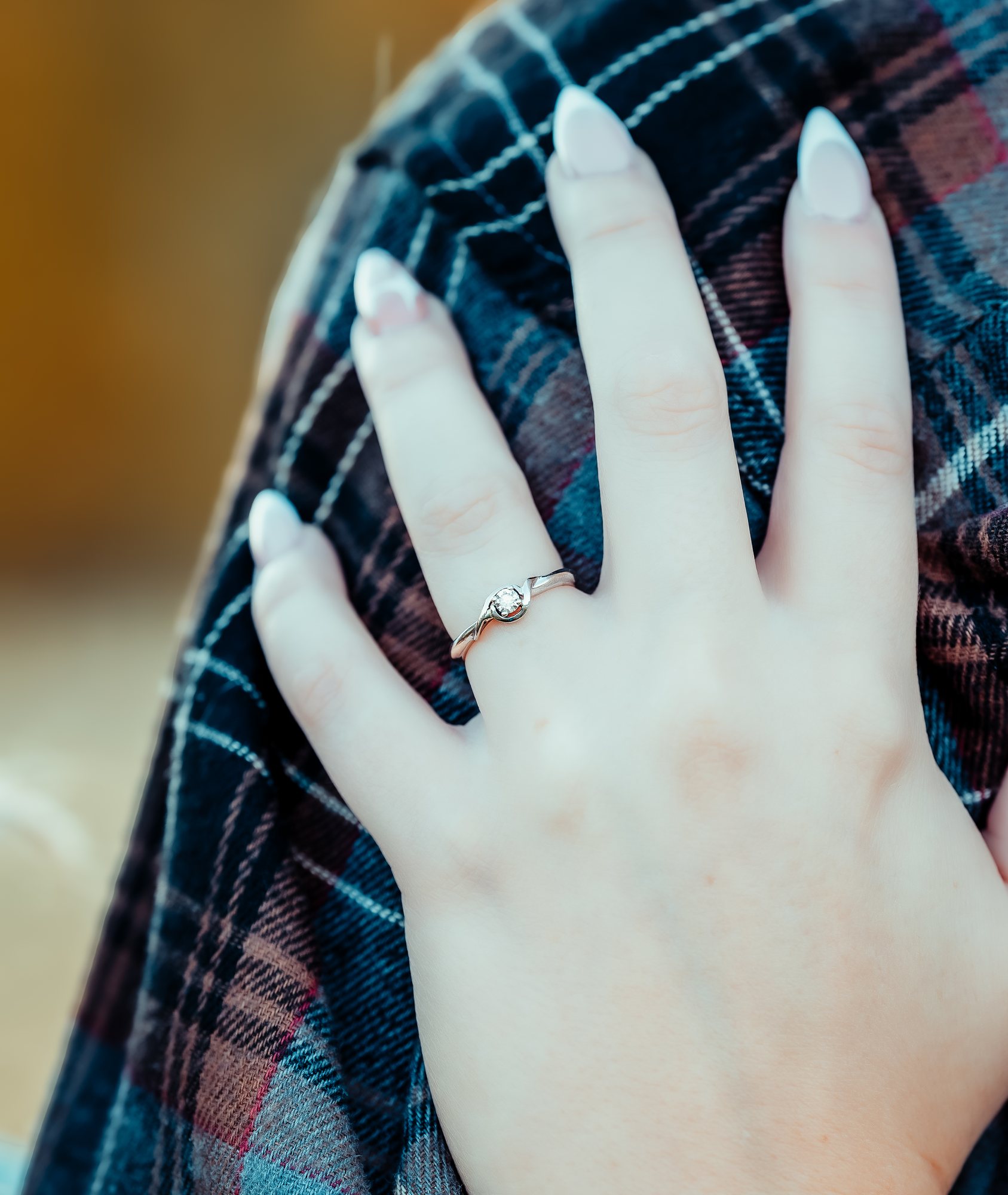 Courtney's hand with her engagement ring, resting on Ken's plaid shirt